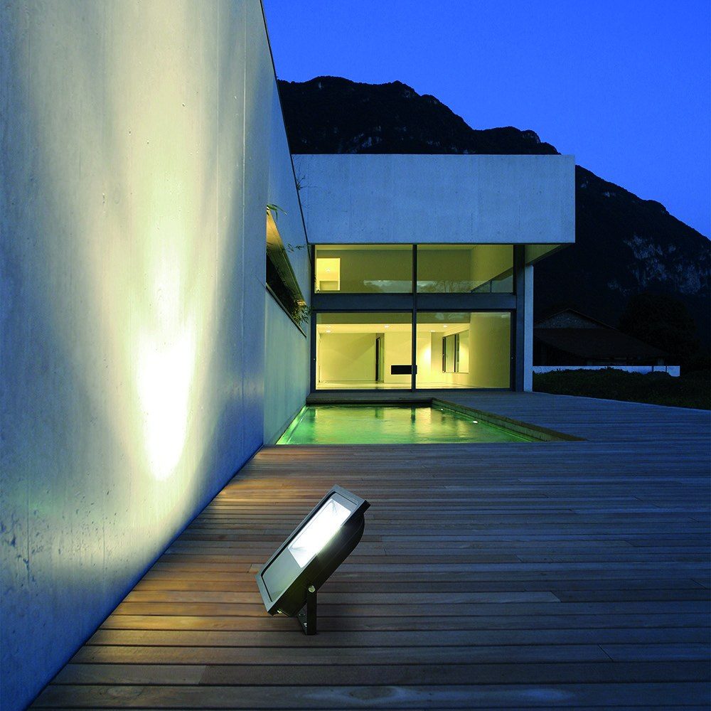 Fachada de vivienda iluminada con proyector exterior junto a la piscina
